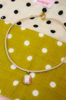 Quin Pendant Necklace in tan cord with iridescent jewel pendant on green dot fabric
