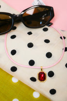 Quin Pendant Necklace in pink cord with red jewel pendant on cream polka dot fabric