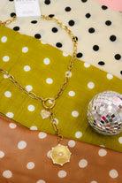 Laney Lariat Gold Charm Necklace, close-up of the gold medallion drop on dot fabric