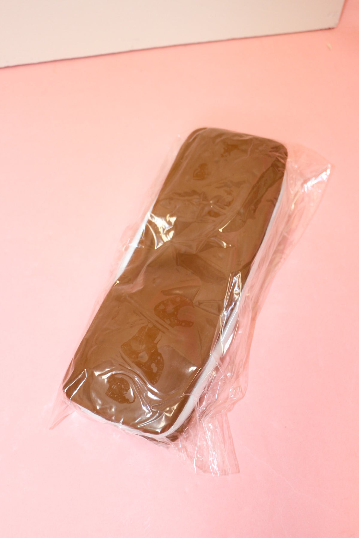 Jumbo ice cream sandwich squishy with brown cookie-style layers and a white center, wrapped on a pink surface.