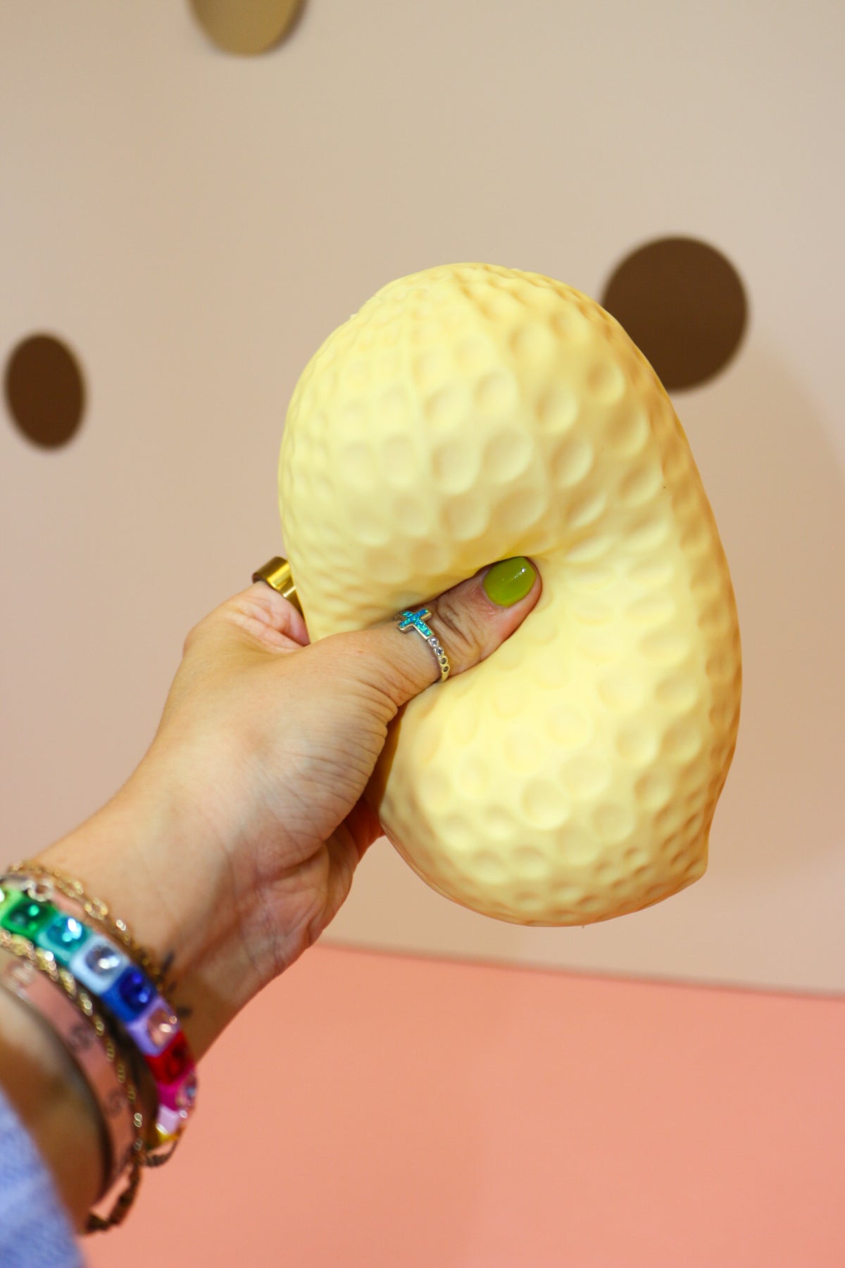 Close-up of a hand pressing into the middle of a textured jumbo peanut-shaped squishy toy.