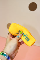 Hand squeezing a golden-yellow butter-stick squishy with green Salted Butter lettering against a dotted backdrop.