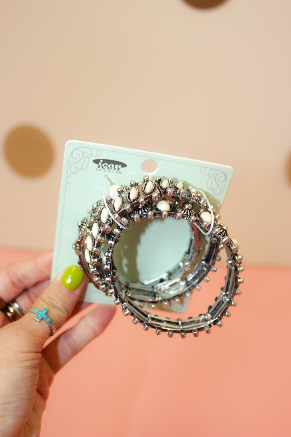 Hand holding three-piece Western bracelet set with white teardrop accents, ornate silver-tone settings, and bead-like details.
