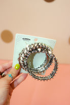 Hand holding three-piece Western bracelet set with white teardrop accents, ornate silver-tone settings, and bead-like details.