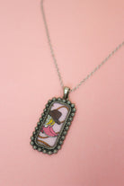 Close-up of Western tag pendant with pink cowboy boot, brown hat, rope illustration, and ornate silver-tone border.