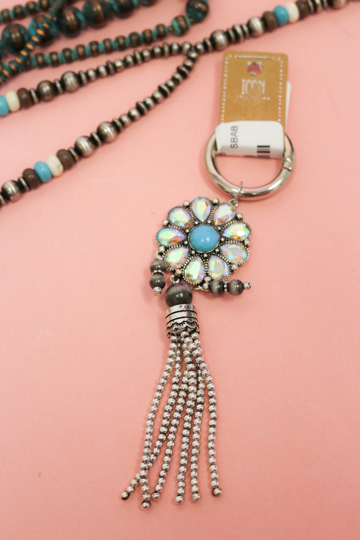 Western keychain with iridescent flower petals, turquoise-colored center, dark bead accents, and silver-tone beaded tassel.