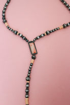 Close-up of silver-tone and pale pink beaded Y necklace with a framed rectangular pink centerpiece and long beaded drop.
