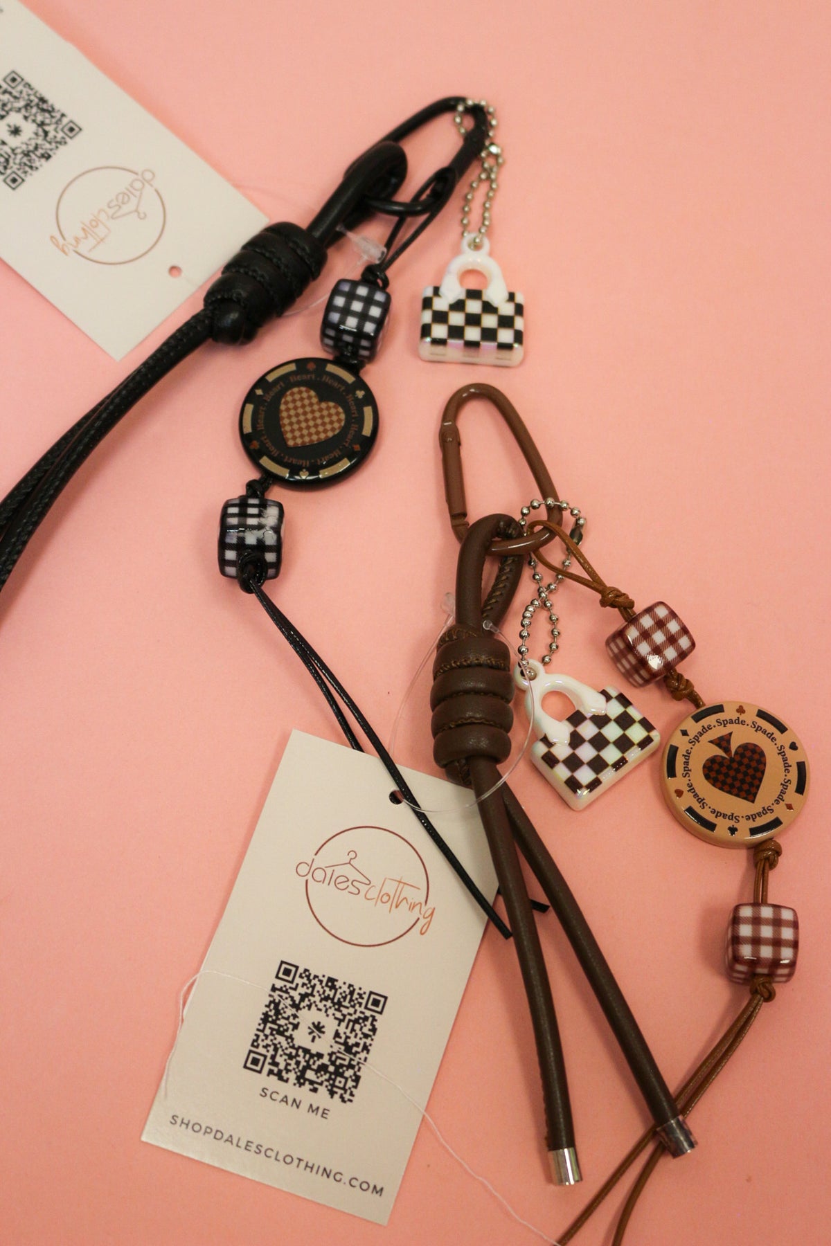 Black and brown Suit Of Spade keychains with gingham beads, spade discs and checkerboard handbag charms on pink.