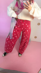 Close front view of the Dotted All Around brick red polka dot barrel jeans with a cream sweater