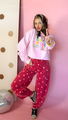 Dotted All Around brick red polka dot barrel jeans worn with a pink graphic sweatshirt, playful pose