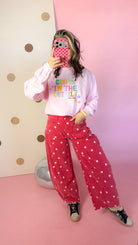 Brick red polka dot barrel jeans and pink sweatshirt, full-length mirror selfie showing the curved leg