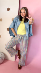 Women's yellow ribbed knit tank with denim shirt and plaid pants, model posing with one leg raised.