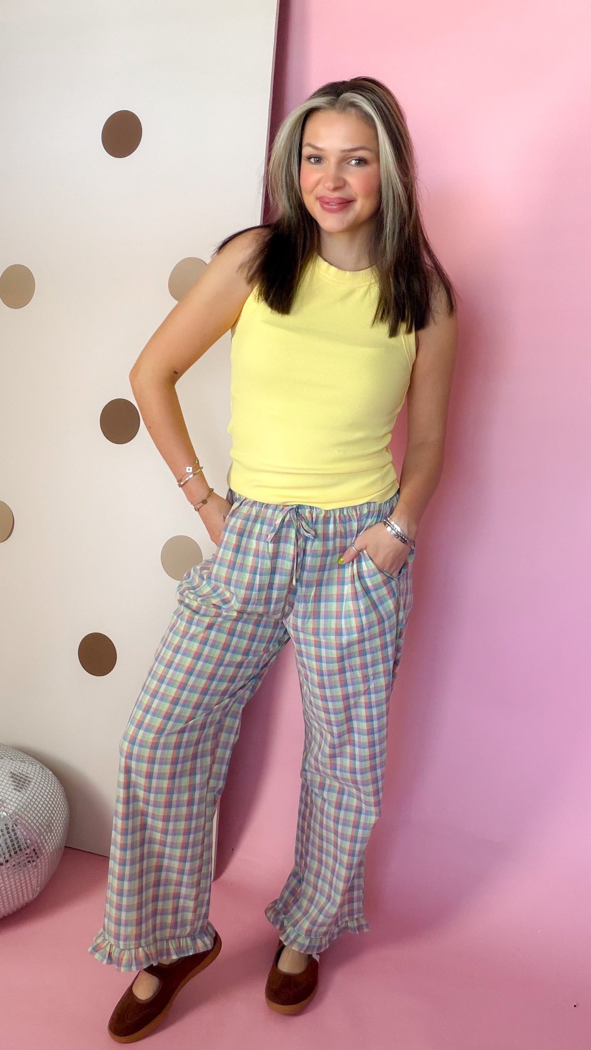 Front view of women's Daisy yellow ribbed knit tank top worn with plaid pants, without an outer layer.
