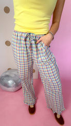 Close-up of plaid pants showing the tie waist, front patch pocket, wide legs, and ruffle hems