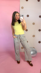 Mirror selfie showing Daisy yellow ribbed tank top styled with plaid wide-leg pants and brown flats.
