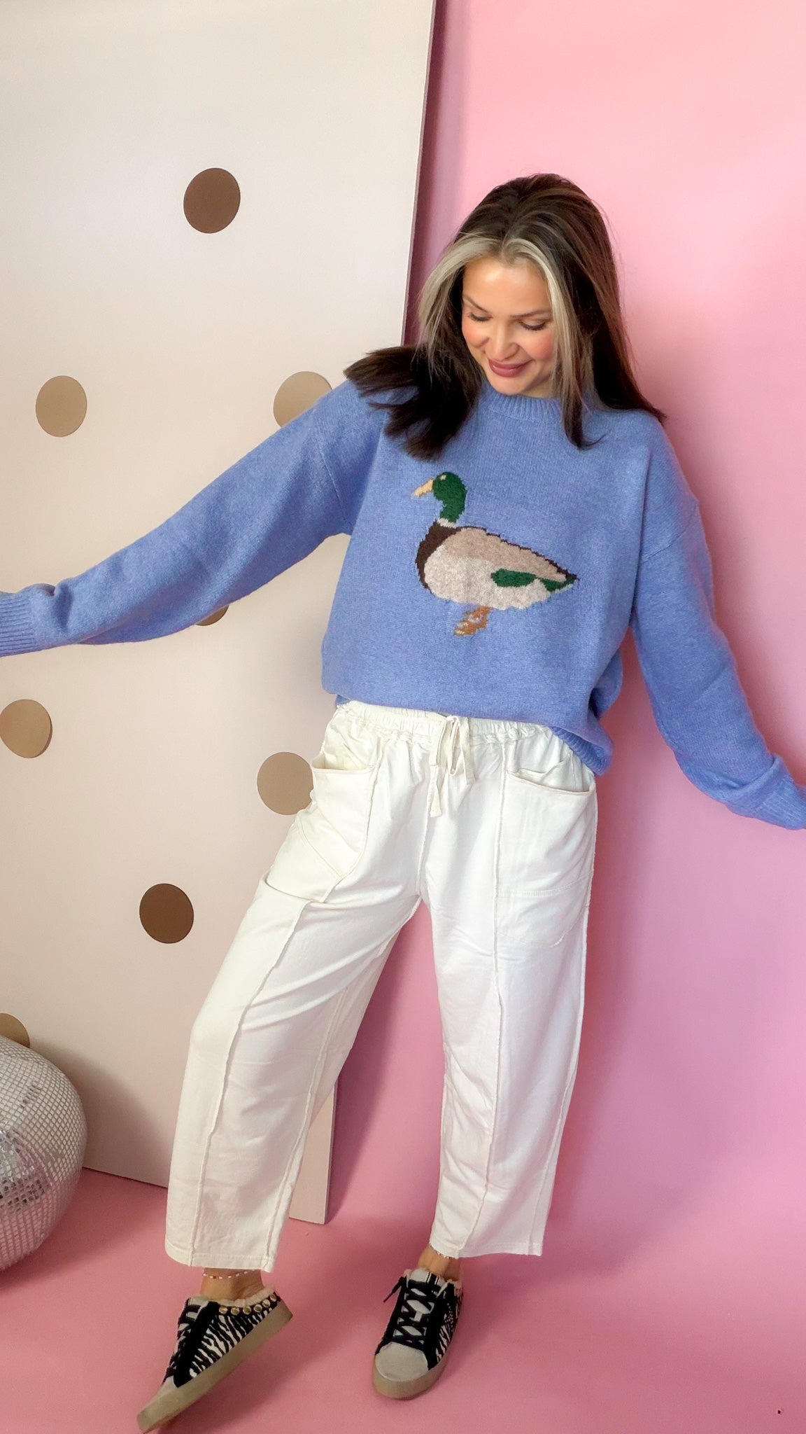 Front view of Ecru barrel pants styled with a blue duck sweater and printed sneakers.