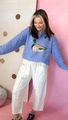 Front view of Ecru drawstring barrel pants with exposed seams, styled with a blue duck sweater.