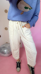 Ecru cotton barrel pants showing the drawstring waistband, front patch pockets and exposed leg seams.