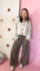 Mocha leopard wide leg pants styled with a cream cropped cardigan and sneakers, front view.