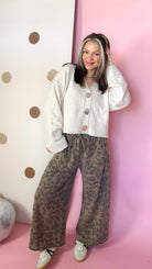 Front view of Easel mocha leopard terry knit pants styled with a cream cardigan and low-top sneakers.