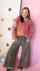 Front view of mocha leopard wide leg pants styled with a striped cardigan, with hands in the side pockets.