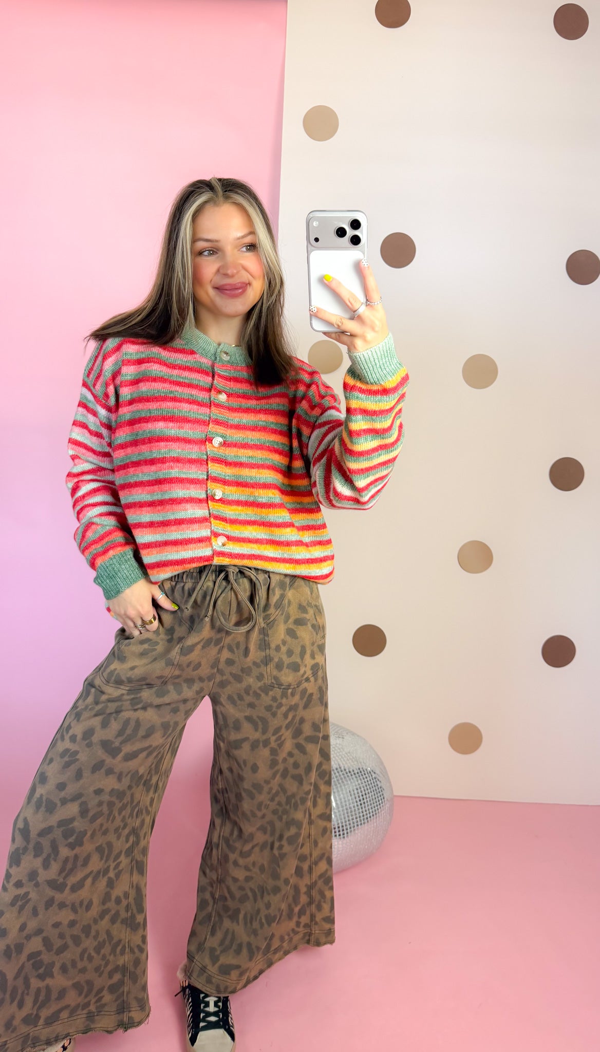 Mirror outfit view of colorful Christmas stripe cardigan with leopard print wide-leg pants and sneakers