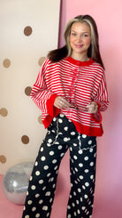 Front view of women's red and ivory striped button sweater with red trim, styled with black polka-dot pants.