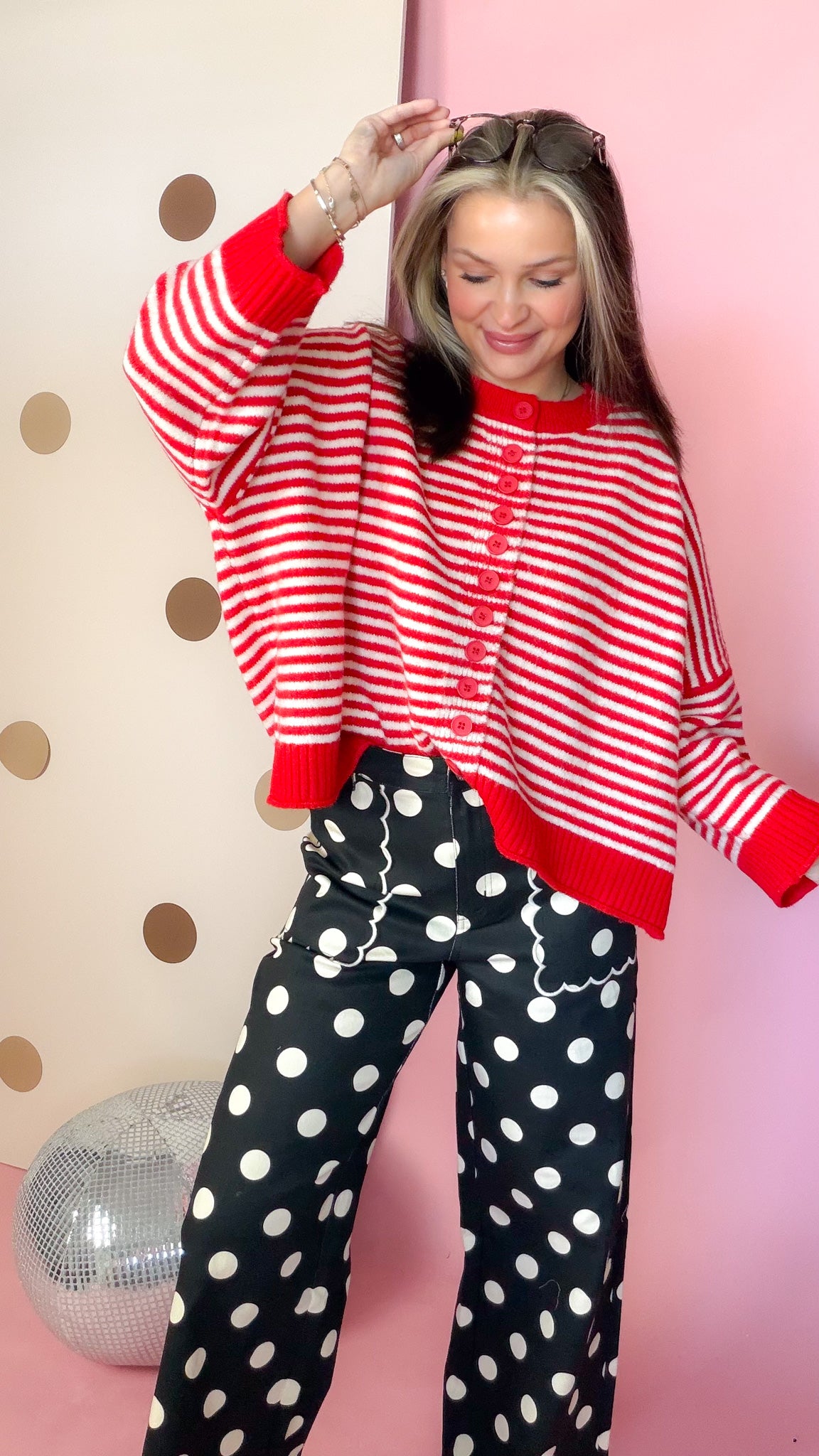 Women's striped button sweater with drop shoulders and long sleeves, shown with one arm raised.