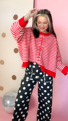 Women's striped button sweater with drop shoulders and long sleeves, shown with one arm raised.