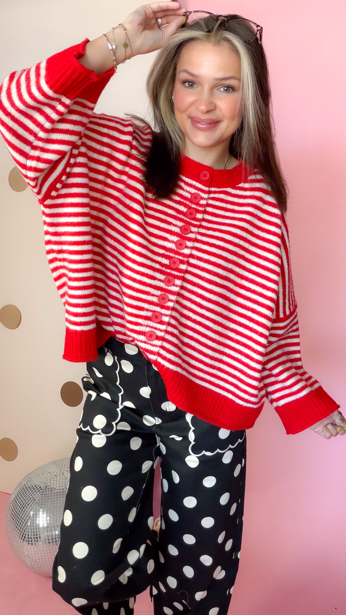 Close front view of red and ivory striped sweater showing red buttons, round neckline, and solid red hem.