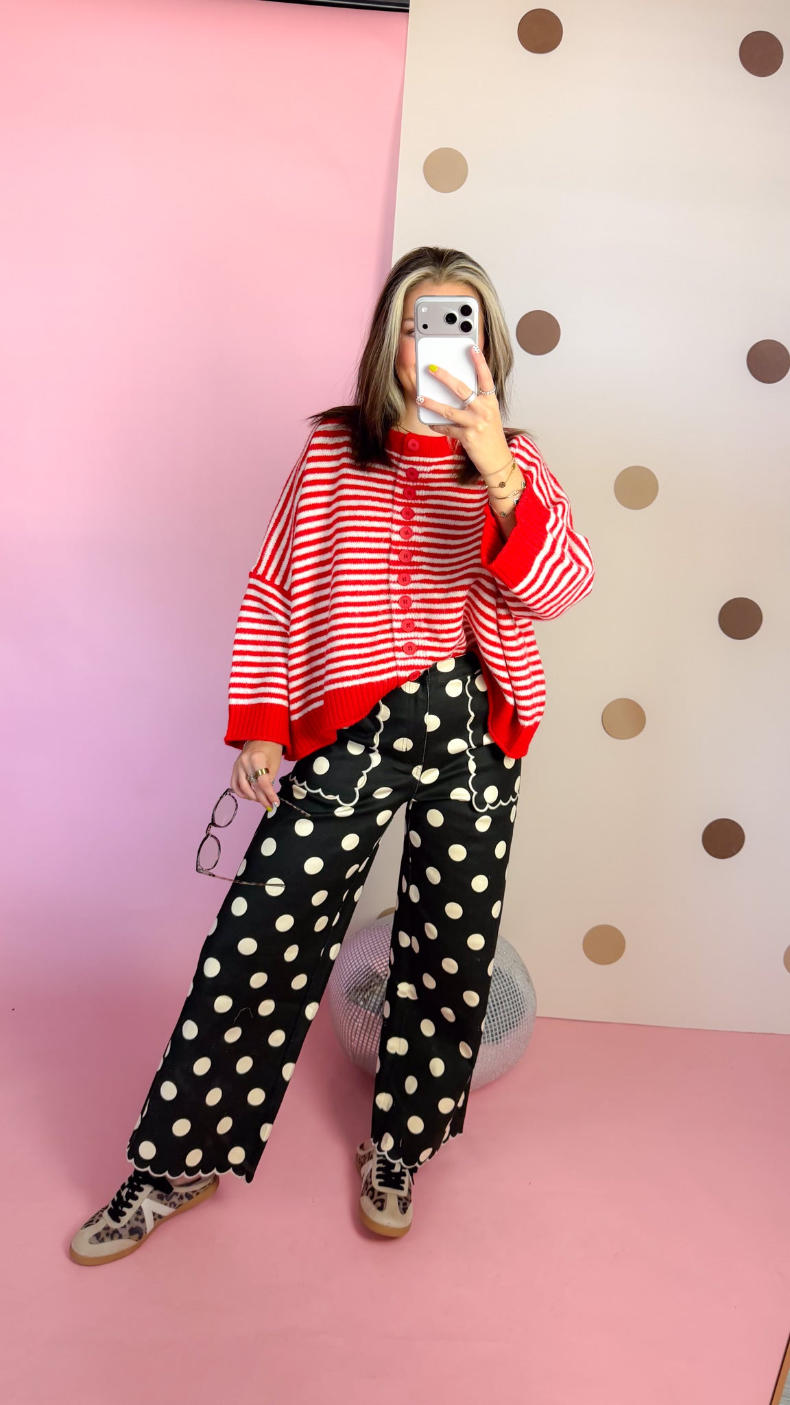 Mirror outfit view of women's red and ivory striped button sweater with polka-dot pants and sneakers.