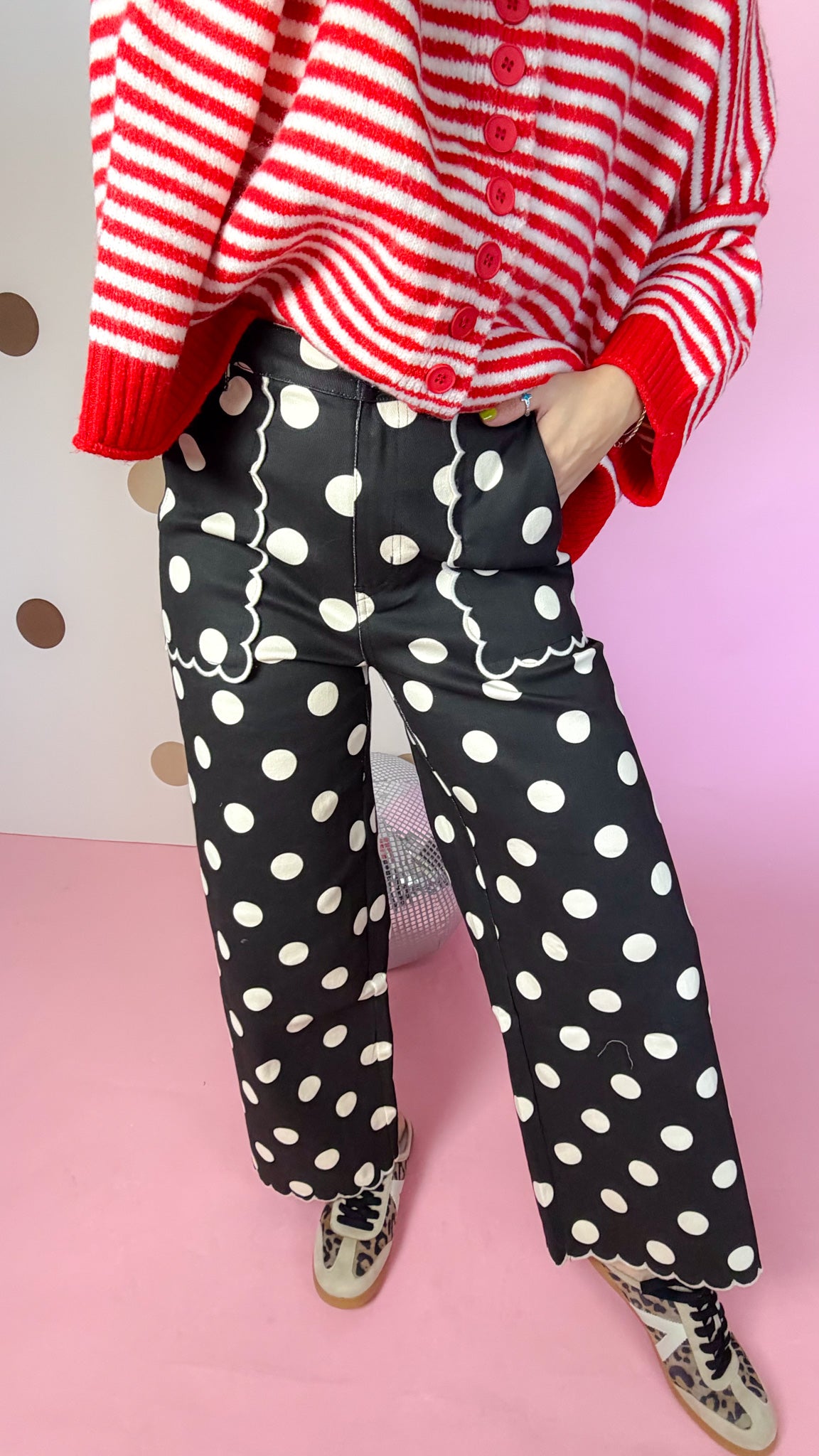 Close-up of black polka dot pants showing scalloped front pockets, wide legs and scalloped hems.