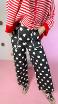 Close-up of black polka dot pants showing scalloped front pockets, wide legs and scalloped hems.