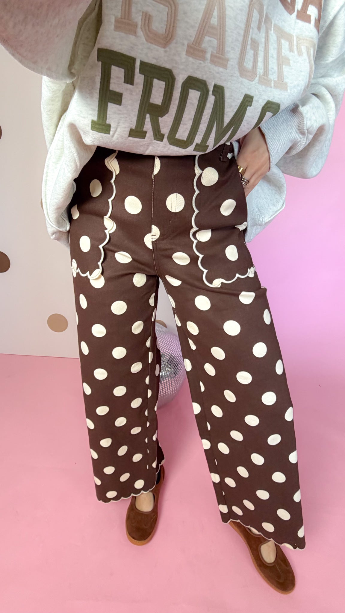 Detail of brown polka dot pants showing scalloped front pocket trim, wide legs and scalloped hems.