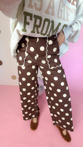 Detail of brown polka dot pants showing scalloped front pocket trim, wide legs and scalloped hems.