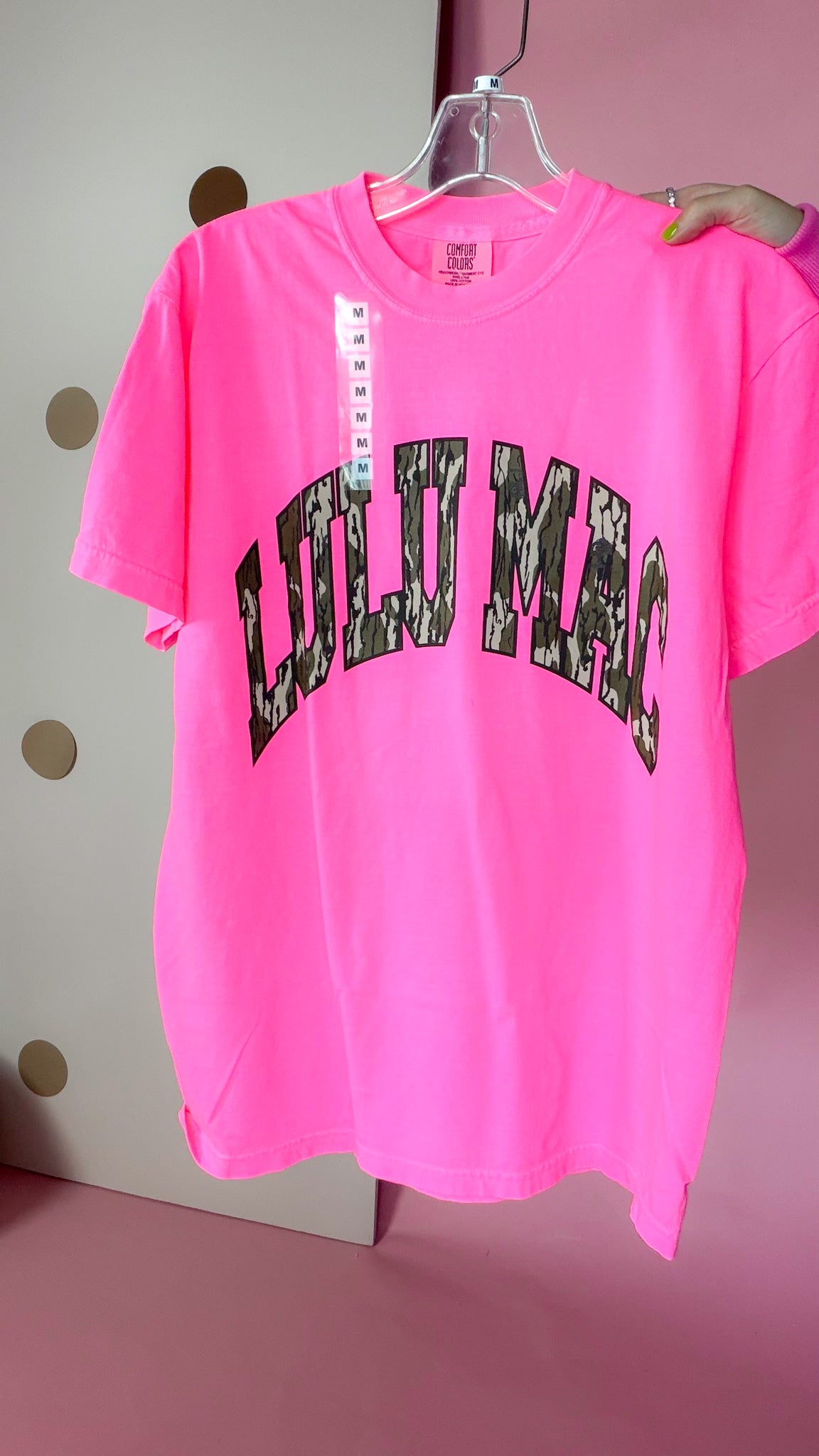 Front of Lulu Mac women's neon pink short-sleeve tee with large arched Bottomland camouflage lettering.
