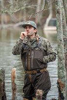Local Boy duck down vest in camo worn over waders by hunter calling ducks in flooded timber