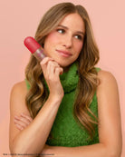 The Grinch x Kitsch Cherry Cheer hair perfume held to the cheek by a model in green