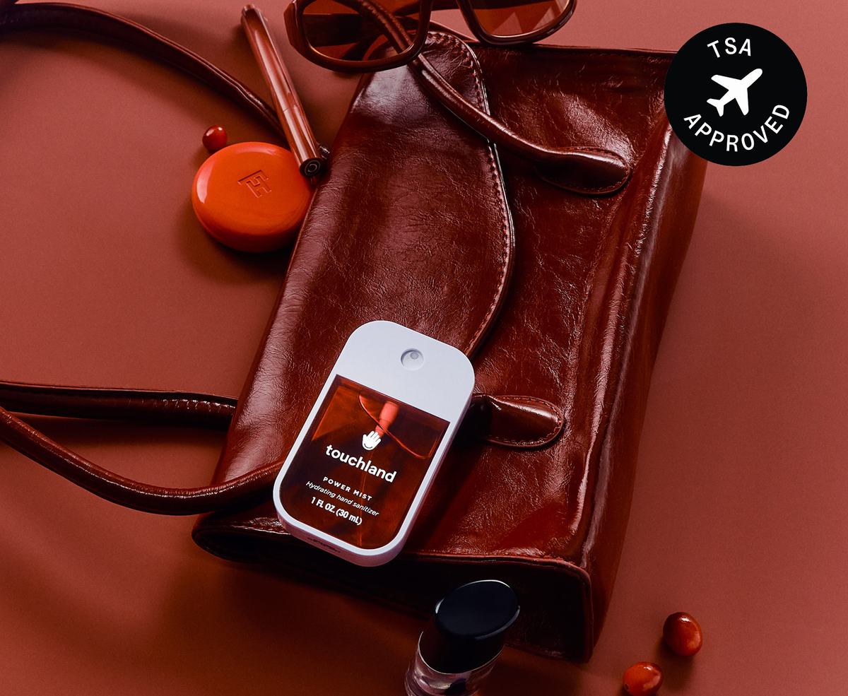 Touchland Cranberry Fizz Power Mist on a red leather bag with TSA approved badge