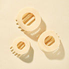 Three Teleties Almond Beige Flat Circle Hair Clips on a cream background