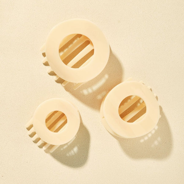 Three Teleties Almond Beige Flat Circle Hair Clips on a cream background