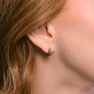 Gold croissant huggie hoop earring worn close to the ear, showing its twisted ridged design.