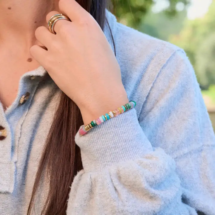 Julia multicolor beaded bracelet with gold accents worn on a wrist beside a light gray knit sleeve.