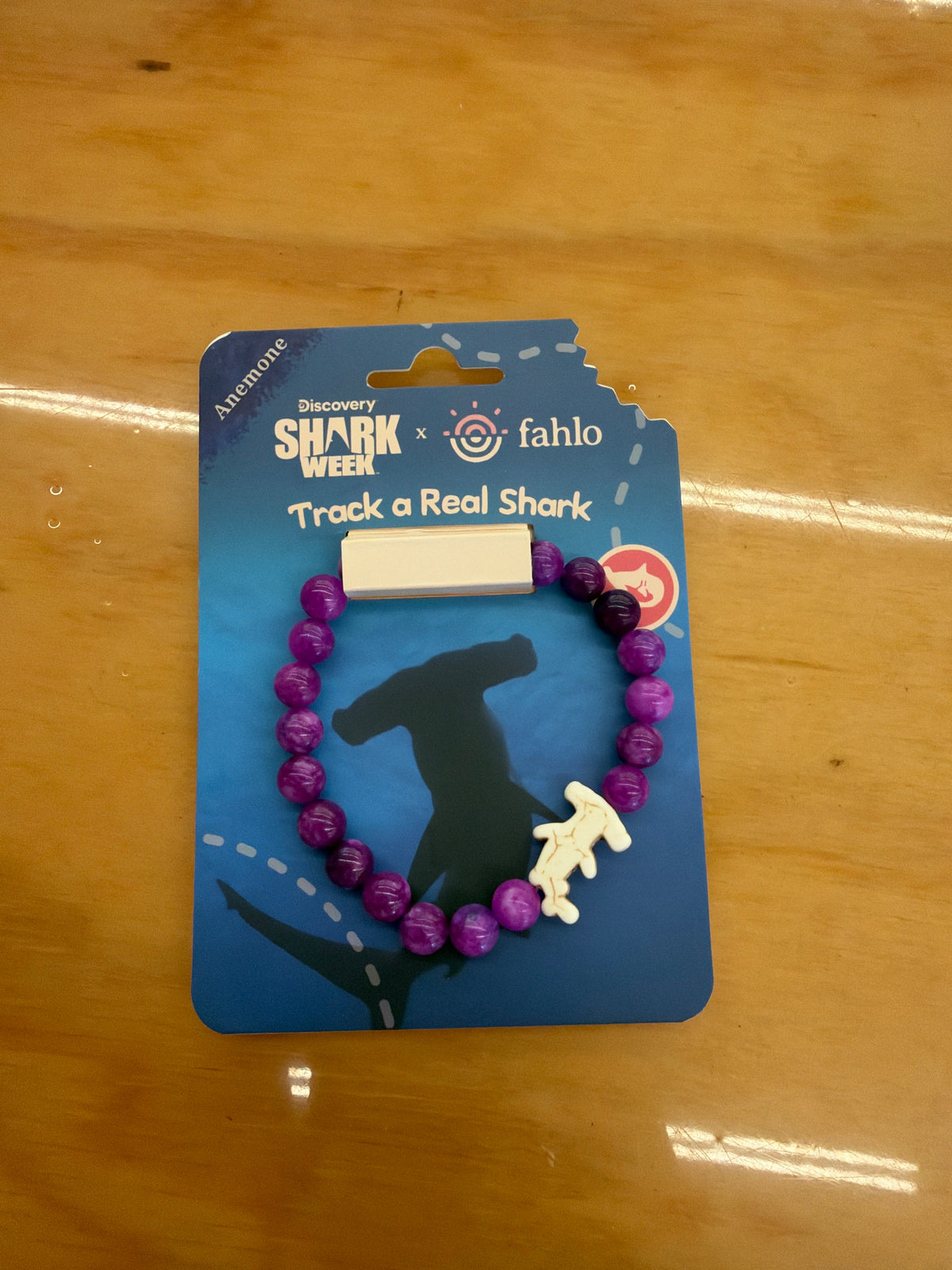Fahlo Voyage Hammerhead Shark Tracking Bracelet in purple beads with shark charm, on its card
