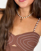 Lolly Pearl Beaded Gold Cross Necklace worn by a smiling model in a brown top