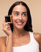 Model holding the black Kitsch Lymphatic Contour Face Brush to her cheek