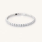 Angled view of a silver-tone tennis bracelet showing clear round stones and the sides of their settings.