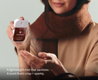 Touchland Salted Caramel Power Mist being sprayed onto a hand, brown scarf