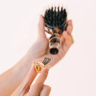Hand removing the cleaning tool from the handle of the Teleties Mini Boar Brush in tortoise