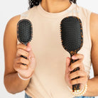 Model holding Teleties Mini and full size Detangler Brushes in tortoise to compare size